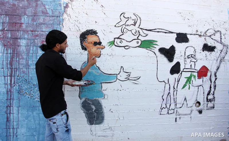 A Palestinian artist paints a mural during a rally marking World Peace Day, in the port of Gaza city, on October 13, 2016. Photo by Ashraf Amra