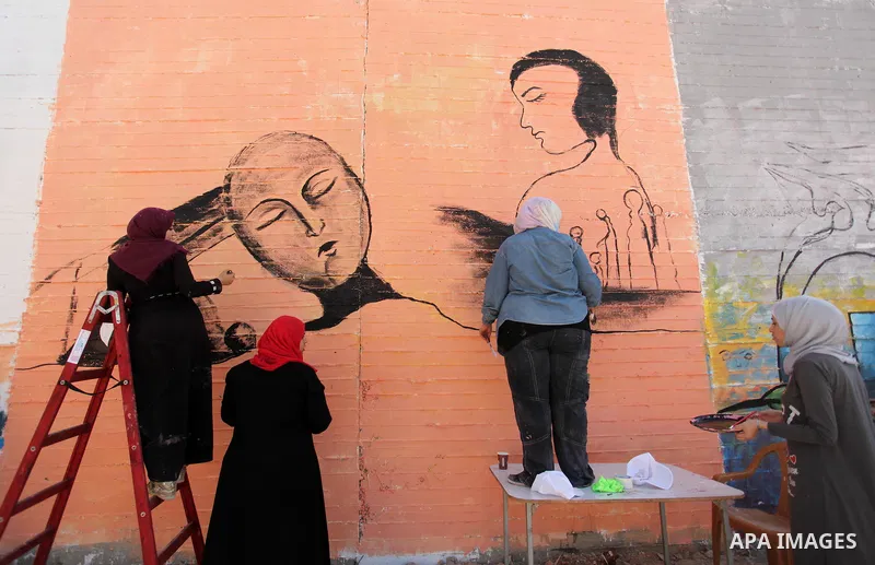 Palestinian artists paint a mural during a rally marking World Peace Day, in the port of Gaza city, on October 13, 2016. Photo by Ashraf Amra