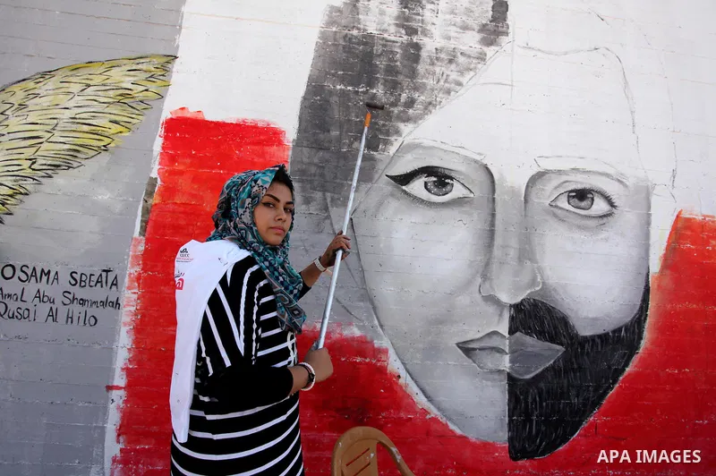A Palestinian artist paints a mural during a rally marking World Peace Day, in the port of Gaza city, on October 13, 2016. Photo by Ashraf Amra