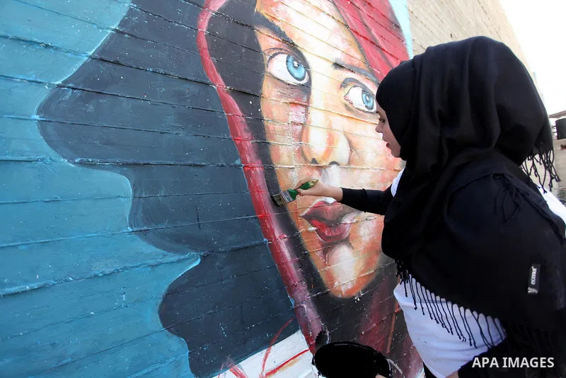 A Palestinian artist paints a mural during a rally marking World Peace Day, in the port of Gaza city, on October 13, 2016. Photo by Ashraf Amra