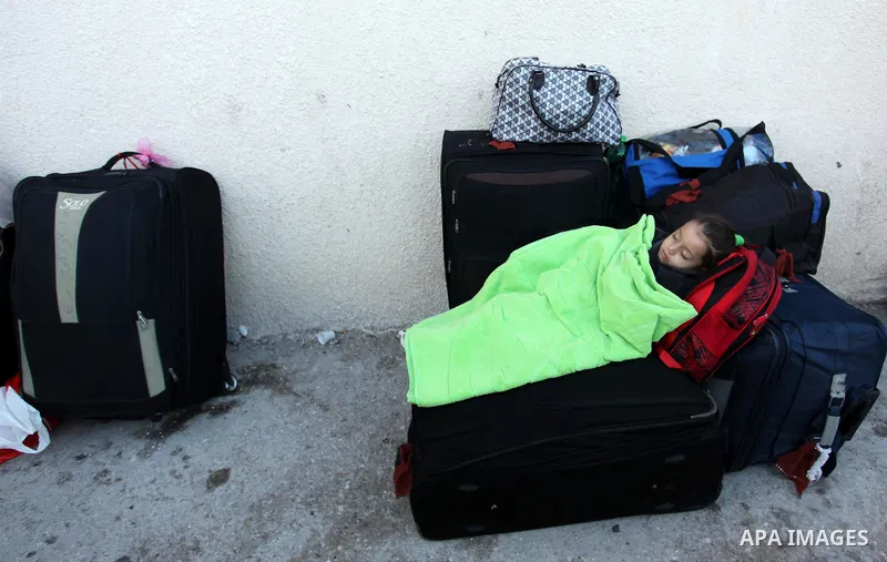 A Palestinian girl sleeps on a suitcase as she waits with her family for a travel permit to cross into Egypt through the Rafah border crossing on October 15, 2016 in the southern Gaza Strip. Egyptian authorities temporar...