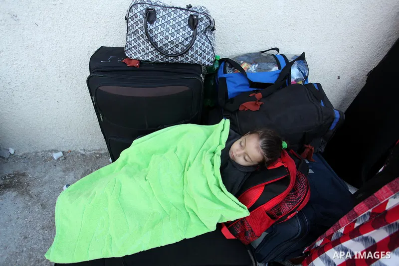 A Palestinian girl sleeps on a suitcase as she waits with her family for a travel permit to cross into Egypt through the Rafah border crossing on October 15, 2016 in the southern Gaza Strip. Egyptian authorities temporar...