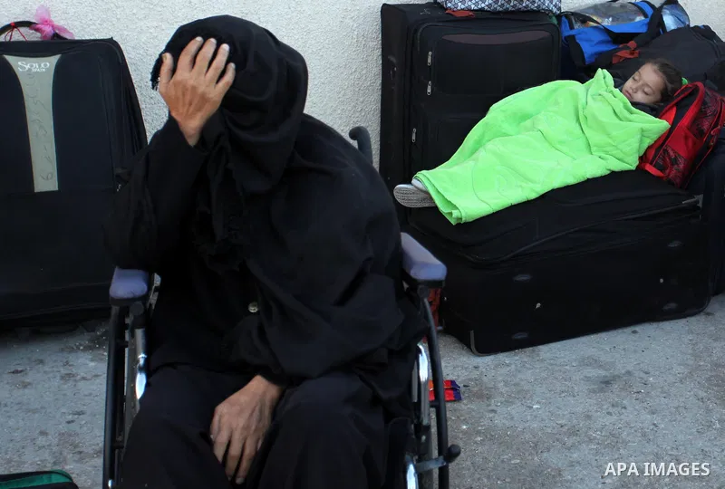A Palestinian girl sleeps on a suitcase as she waits with her family for a travel permit to cross into Egypt through the Rafah border crossing on October 15, 2016 in the southern Gaza Strip. Egyptian authorities temporar...