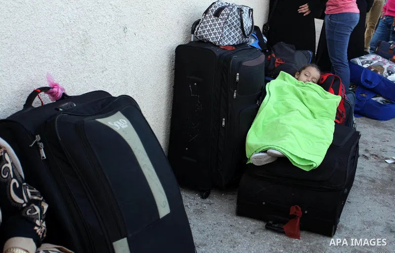 A Palestinian girl sleeps on a suitcase as she waits with her family for a travel permit to cross into Egypt through the Rafah border crossing on October 15, 2016 in the southern Gaza Strip. Egyptian authorities temporar...