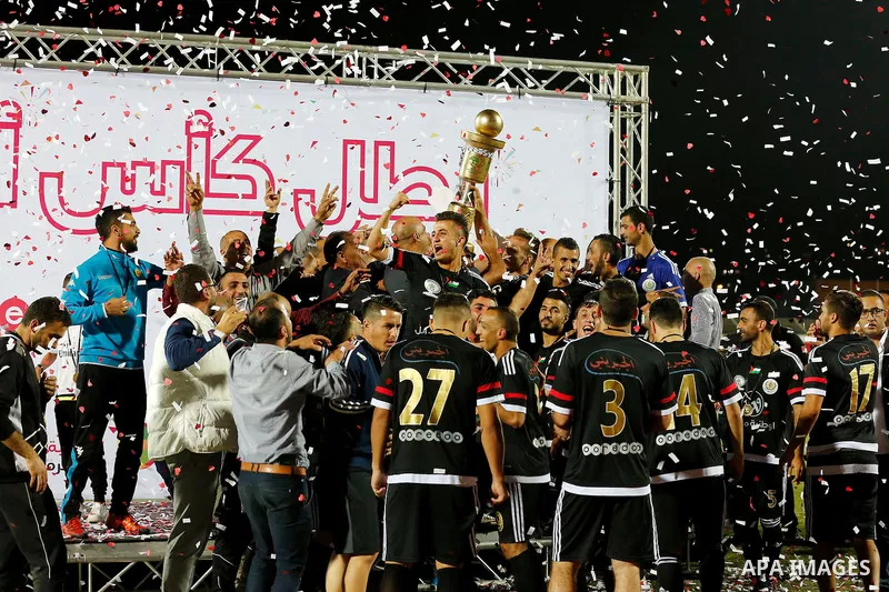 Shabab Hebron players celebrate with the trophy after winning the final match of the Palestinian Cup (Abu Ammar Cup), in the West Bank city of Hebron, on October 15, 2016. Photo by Wisam Hashlamoun