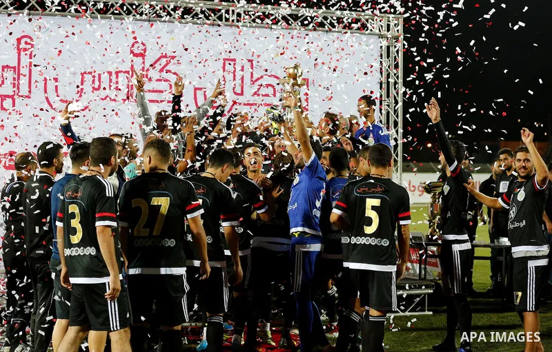Shabab Hebron players celebrate with the trophy after winning the final match of the Palestinian Cup (Abu Ammar Cup), in the West Bank city of Hebron, on October 15, 2016. Photo by Wisam Hashlamoun