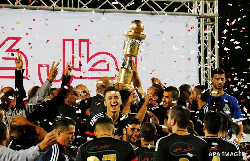 Shabab Hebron players celebrate with the trophy after winning the final match of the Palestinian Cup (Abu Ammar Cup), in the West Bank city of Hebron, on October 15, 2016. Photo by Wisam Hashlamoun