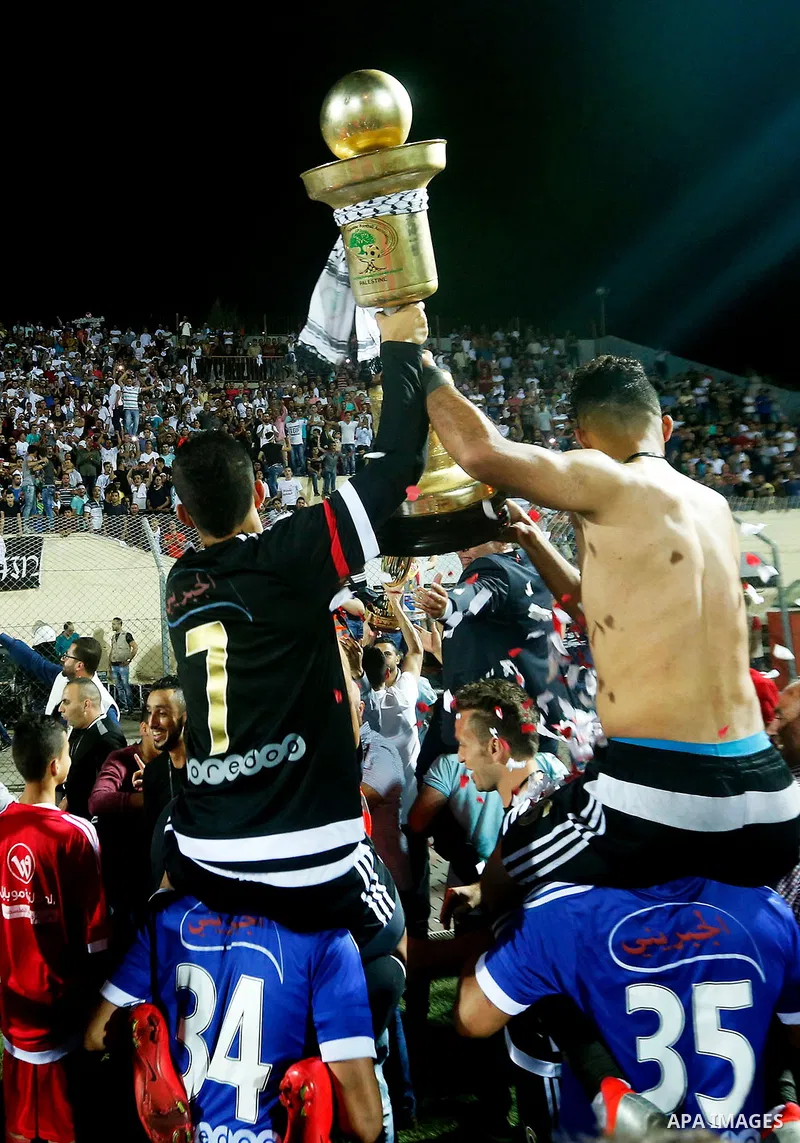 Shabab Hebron players celebrate with the trophy after winning the final match of the Palestinian Cup (Abu Ammar Cup), in the West Bank city of Hebron, on October 15, 2016. Photo by Wisam Hashlamoun