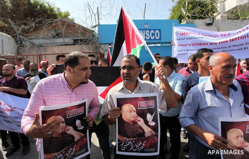 Palestinians hold posters of Mohammad El Halabi, World Vision's manager of operations in Gaza who was accused by Israel of funnelling millions of dollars in aid money to Hamas, during a protest in solidarity with El Hala...