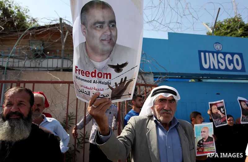 Palestinians hold posters of Mohammad El Halabi, World Vision's manager of operations in Gaza who was accused by Israel of funnelling millions of dollars in aid money to Hamas, during a protest in solidarity with El Hala...