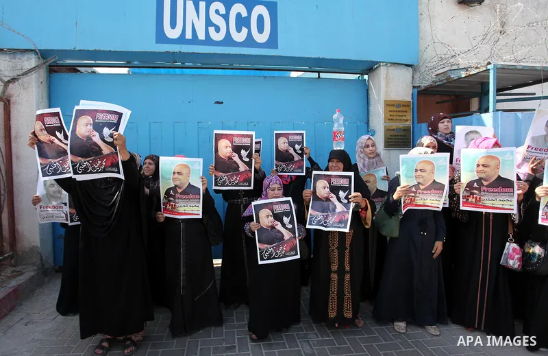Palestinians hold posters of Mohammad El Halabi, World Vision's manager of operations in Gaza who was accused by Israel of funnelling millions of dollars in aid money to Hamas, during a protest in solidarity with El Hala...