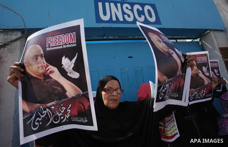 Palestinians hold posters of Mohammad El Halabi, World Vision's manager of operations in Gaza who was accused by Israel of funnelling millions of dollars in aid money to Hamas, during a protest in solidarity with El Hala...