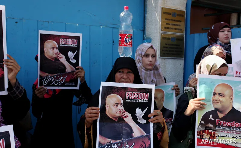 Palestinians hold posters of Mohammad El Halabi, World Vision's manager of operations in Gaza who was accused by Israel of funnelling millions of dollars in aid money to Hamas, during a protest in solidarity with El Hala...