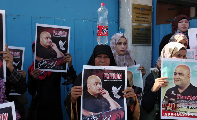 Palestinians hold posters of Mohammad El Halabi, World Vision's manager of operations in Gaza who was accused by Israel of funnelling millions of dollars in aid money to Hamas, during a protest in solidarity with El Hala...