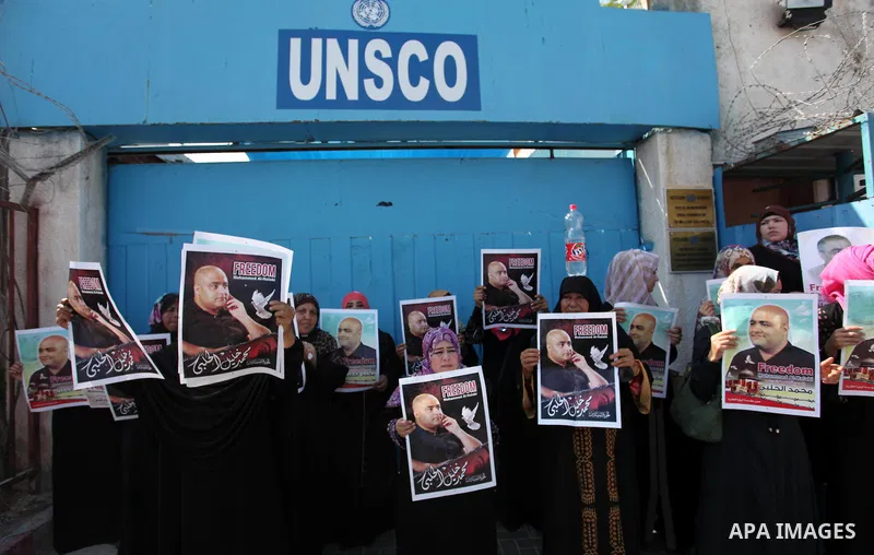 Palestinians hold posters of Mohammad El Halabi, World Vision's manager of operations in Gaza who was accused by Israel of funnelling millions of dollars in aid money to Hamas, during a protest in solidarity with El Hala...