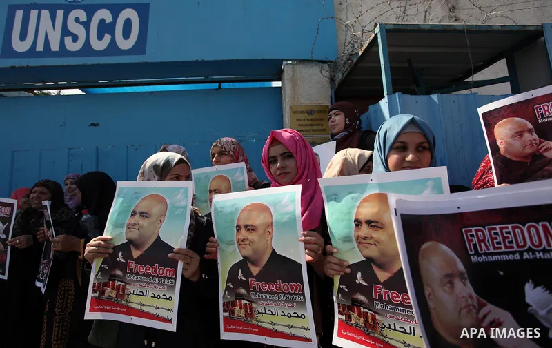 Palestinians hold posters of Mohammad El Halabi, World Vision's manager of operations in Gaza who was accused by Israel of funnelling millions of dollars in aid money to Hamas, during a protest in solidarity with El Hala...