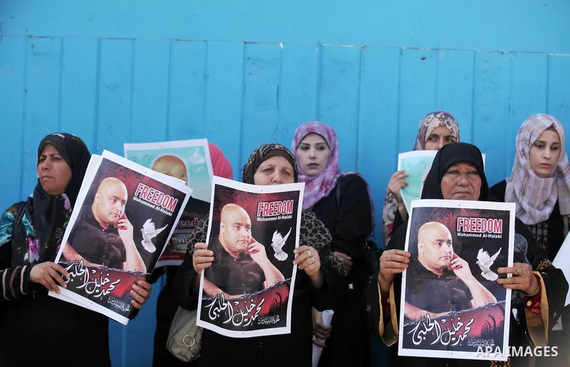 Palestinians hold posters of Mohammad El Halabi, World Vision's manager of operations in Gaza who was accused by Israel of funnelling millions of dollars in aid money to Hamas, during a protest in solidarity with El Hala...