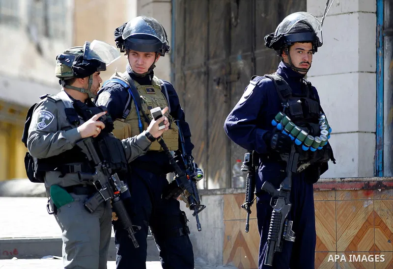 Israeli soldiers stand guard as Israeli settlers walk to visit the Jewish shrine of Atnaeil Ben Kinaz during the Jewish Sukkot holiday or the feast of the Tabernacles in a Palestinian neighbourhood of the divided West Ba...