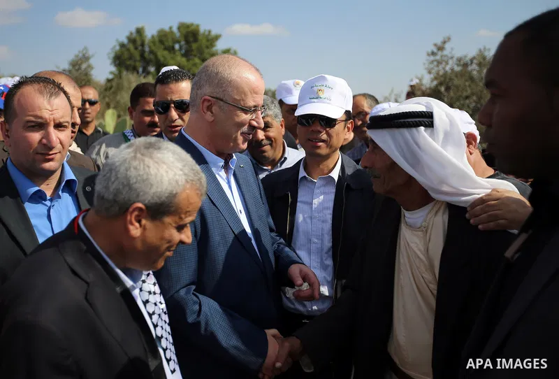 Palestinian Prime Minister Rami Hamdallah takes part during harvest season at a farm in the West Bank city of Qalqilya, on Oct. 22, 2016. Photo by Prime Minister Office