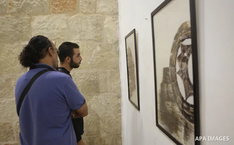 Palestinians attend a drawing exhibition titled "Tales of coffee-flavored", in the West Bank city of Ramallah, on October 25, 2016. Photo by Shadi Hatem