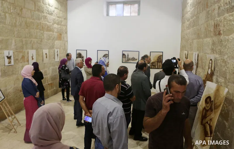 Palestinians attend a drawing exhibition titled "Tales of coffee-flavored", in the West Bank city of Ramallah, on October 25, 2016. Photo by Shadi Hatem