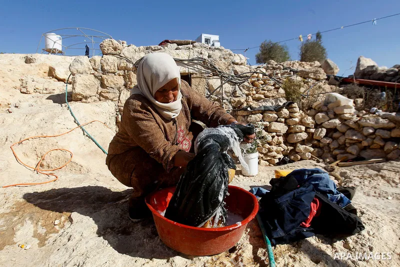 A Palestinian woman of Hawamdeh family washes clothes outside a cave she lives in, in West Bank village of Mufagara, south of Hebron on Oct. 25, 2016. Photo by Wisam Hashlamoun