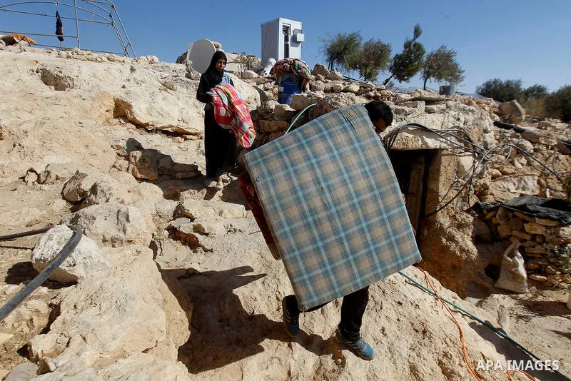 Palestinians of Hawamdeh family carry their belongings outside a cave they lives in, in West Bank village of Mufagara, south of Hebron on Oct. 25, 2016. Photo by Wisam Hashlamoun