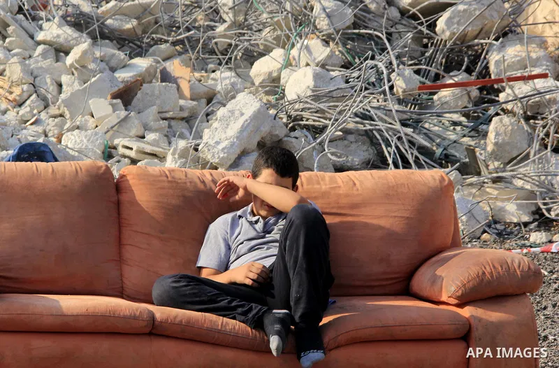 A Palestinian boy reacts as he sit on the sofa following Israeli forces demolished his family house which Israeli authorities said it was built without a permit in Wadi Qaddum in the East Jerusalem neighborhood of Silwan...