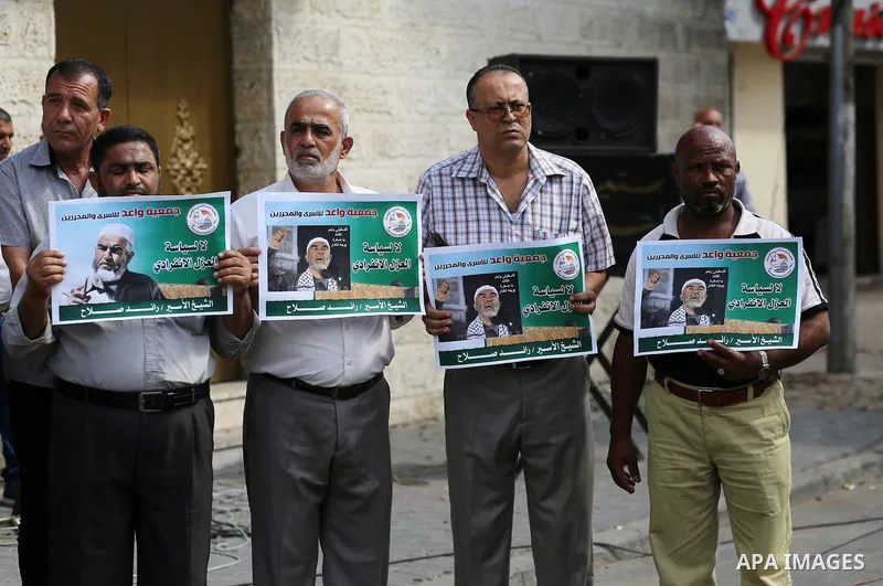 Palestinian members of Hamas legislative council and members of the factions hold banners during a protest to show solidarity with Leader of the northern Islamic Movement Sheikh Raed Salah who is in solitary confinement...