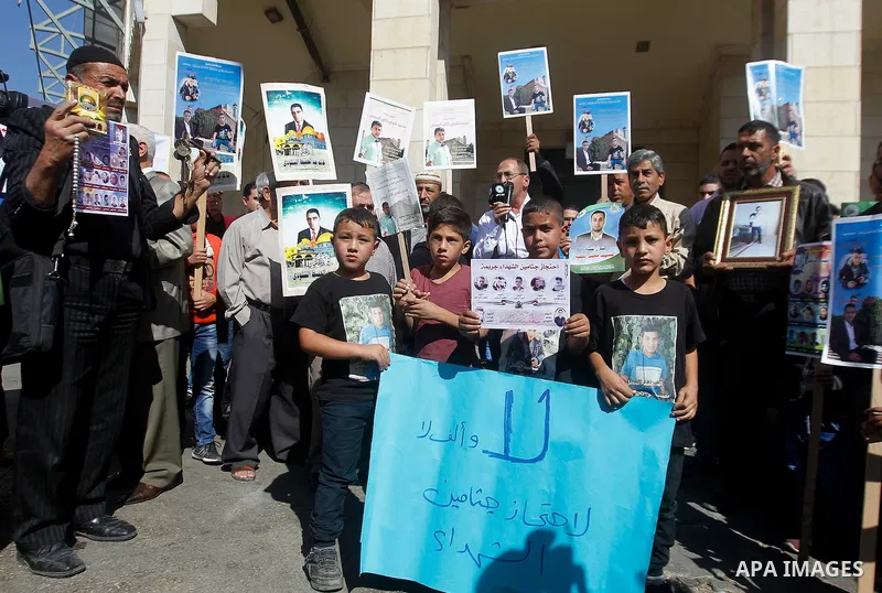 Palestinians hold banners during a protest demanding Israel return the bodies of Palestinians who allegedly stabbed Israelis, in the West Bank city of Hebron, on Oct. 28, 2016. Photo by Wisam Hashlamoun