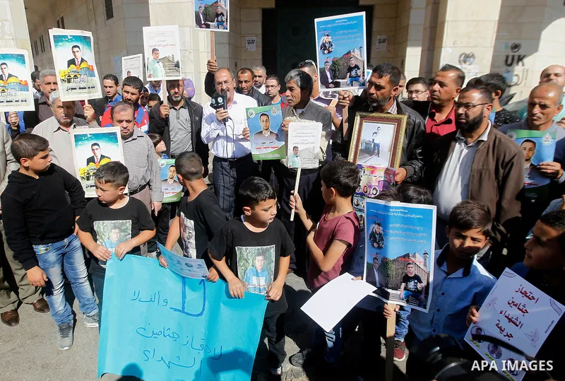 Palestinians hold banners during a protest demanding Israel return the bodies of Palestinians who allegedly stabbed Israelis, in the West Bank city of Hebron, on Oct. 28, 2016. Photo by Wisam Hashlamoun