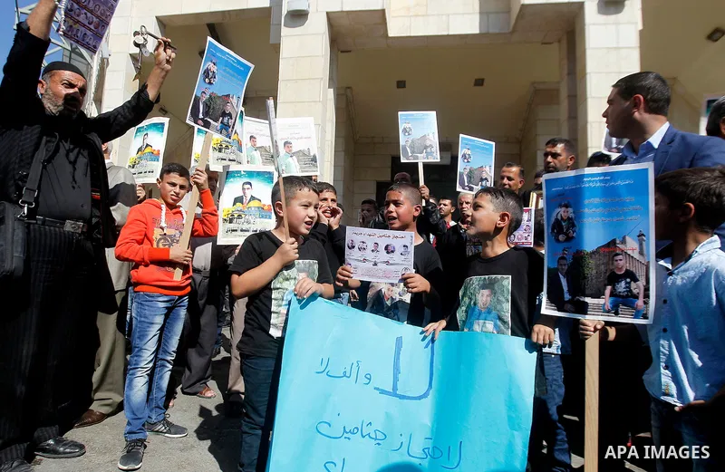 Palestinians hold banners during a protest demanding Israel return the bodies of Palestinians who allegedly stabbed Israelis, in the West Bank city of Hebron, on Oct. 28, 2016. Photo by Wisam Hashlamoun
