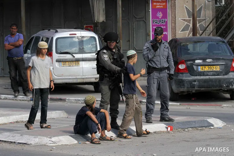 An Israeli border policeman disperses young settlers during a demonstration against Palestinian stones throwers on October 28, 2016 on the main road of the village of Hawara in the northern West Bank. Photo by Nedal Esht...