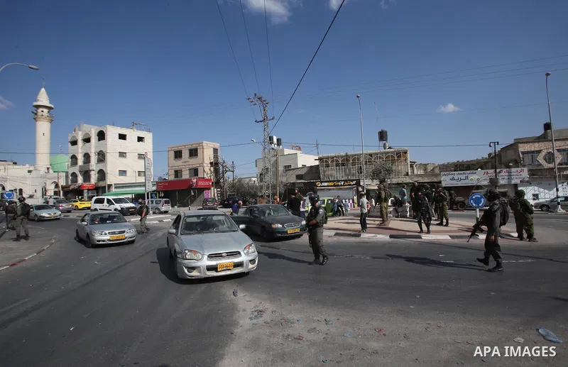 Israeli security forces stand guard as settlers demonstrate against Palestinian stones throwers on October 28, 2016 on the main road of the village of Hawara in the northern West Bank. Photo by Nedal Eshtayah