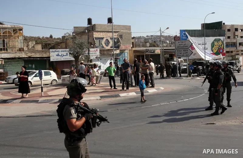 Israeli security forces stand guard as settlers demonstrate against Palestinian stones throwers on October 28, 2016 on the main road of the village of Hawara in the northern West Bank. Photo by Nedal Eshtayah
