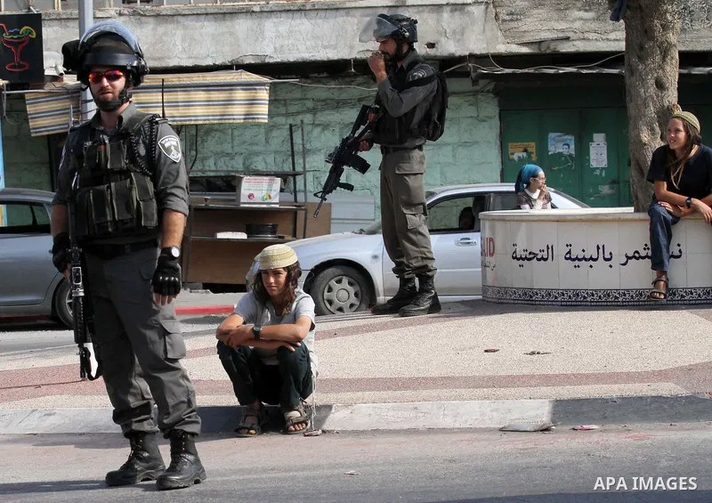Israeli security forces stand guard as settlers demonstrate against Palestinian stones throwers on October 28, 2016 on the main road of the village of Hawara in the northern West Bank. Photo by Nedal Eshtayah
