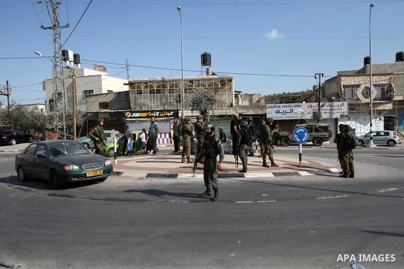 Israeli security forces stand guard as settlers demonstrate against Palestinian stones throwers on October 28, 2016 on the main road of the village of Hawara in the northern West Bank. Photo by Nedal Eshtayah