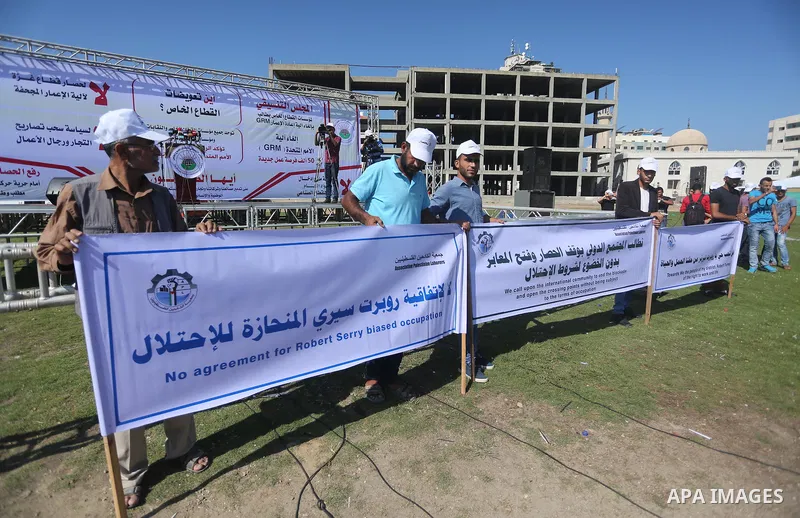 Palestinians hold banners during a protest against the United Nations mechanism for reconstruction and the Israeli blockade of the Gaza Strip, in Gaza City, on October 29, 2016. Photo by Mohammed Asad