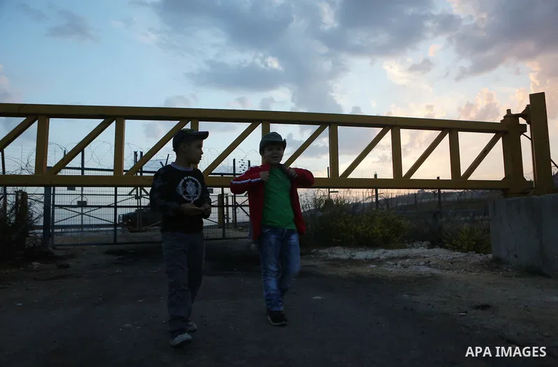 Palestinians wait to allow them to cross their farms during harvest season near the Israeli controversial separation wall in the village of Biddu, north west of Jerusalem, on October 31, 2016. Photo by Shadi Hatem