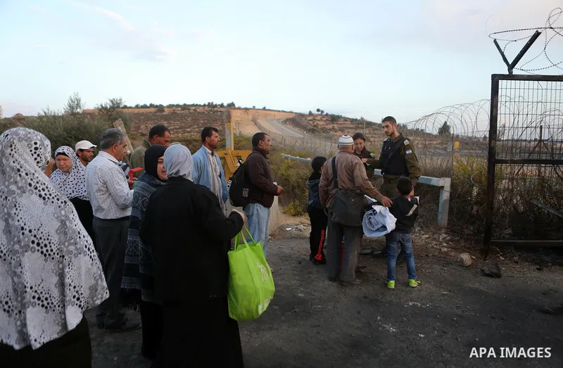Israeli soldiers check the identity cards of Palestinians before allowing them to cross their farms during harvest season, near the Israeli controversial separation wall in the village of Biddu, north west of Jerusalem,...