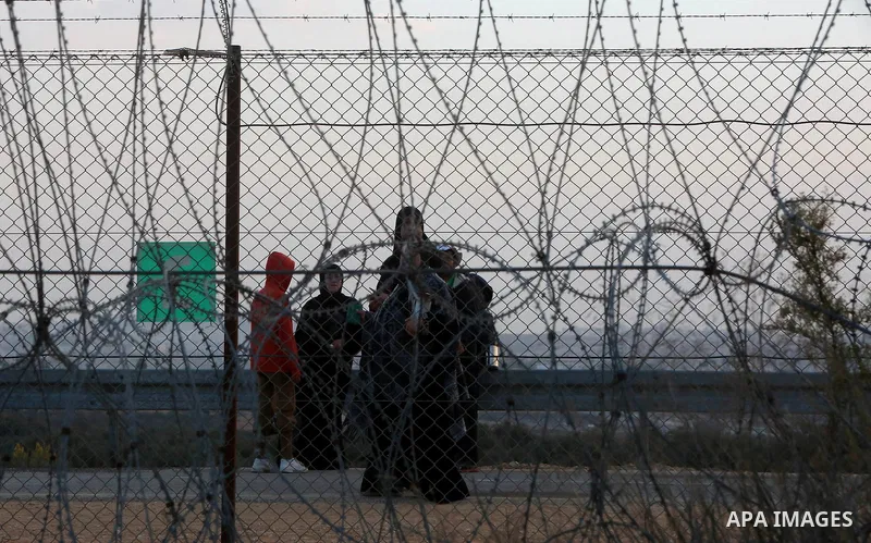 Palestinians wait to allow them to cross their farms during harvest season near the Israeli controversial separation wall in the village of Biddu, north west of Jerusalem, on October 31, 2016. Photo by Shadi Hatem