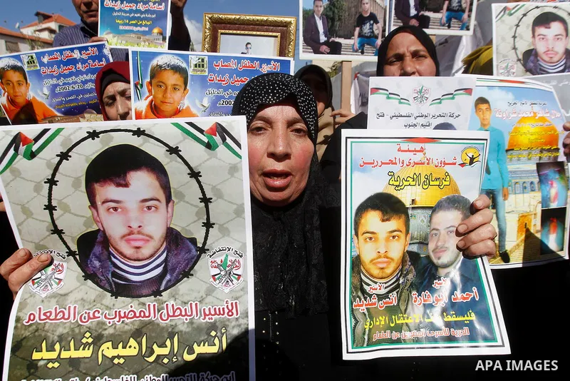 Palestinians hold banners during a protest to show solidarity with Palestinian prisoners in Israeli jails, in front of Red cross office in the West Bank city of Hebron, on October 31, 2016. Photo by Wisam Hashlamoun