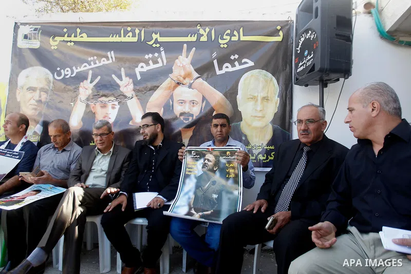 Palestinians hold banners during a protest to show solidarity with Palestinian prisoners in Israeli jails, in front of Red cross office in the West Bank city of Hebron, on October 31, 2016. Photo by Wisam Hashlamoun
