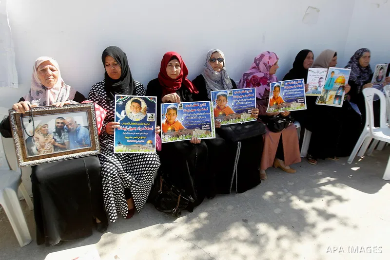 Palestinians hold banners during a protest to show solidarity with Palestinian prisoners in Israeli jails, in front of Red cross office in the West Bank city of Hebron, on October 31, 2016. Photo by Wisam Hashlamoun