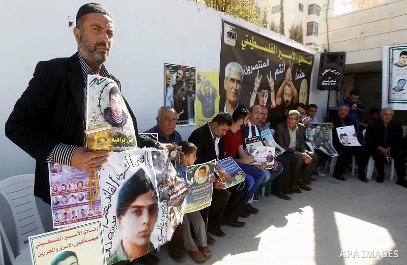 Palestinians hold banners during a protest to show solidarity with Palestinian prisoners in Israeli jails, in front of Red cross office in the West Bank city of Hebron, on October 31, 2016. Photo by Wisam Hashlamoun