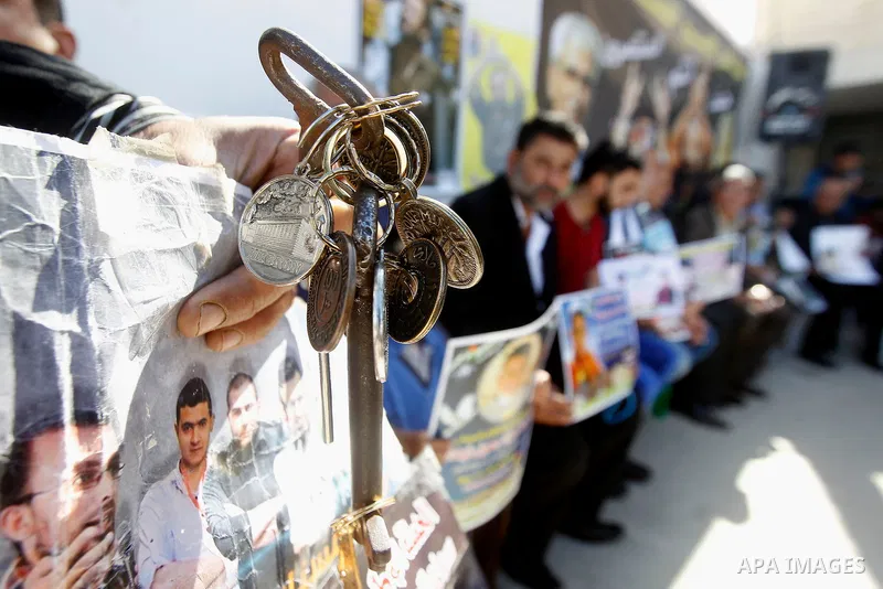 Palestinians hold banners during a protest to show solidarity with Palestinian prisoners in Israeli jails, in front of Red cross office in the West Bank city of Hebron, on October 31, 2016. Photo by Wisam Hashlamoun