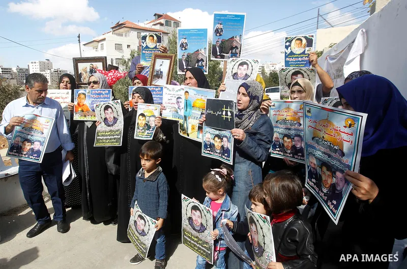 Palestinians hold banners during a protest to show solidarity with Palestinian prisoners in Israeli jails, in front of Red cross office in the West Bank city of Hebron, on October 31, 2016. Photo by Wisam Hashlamoun