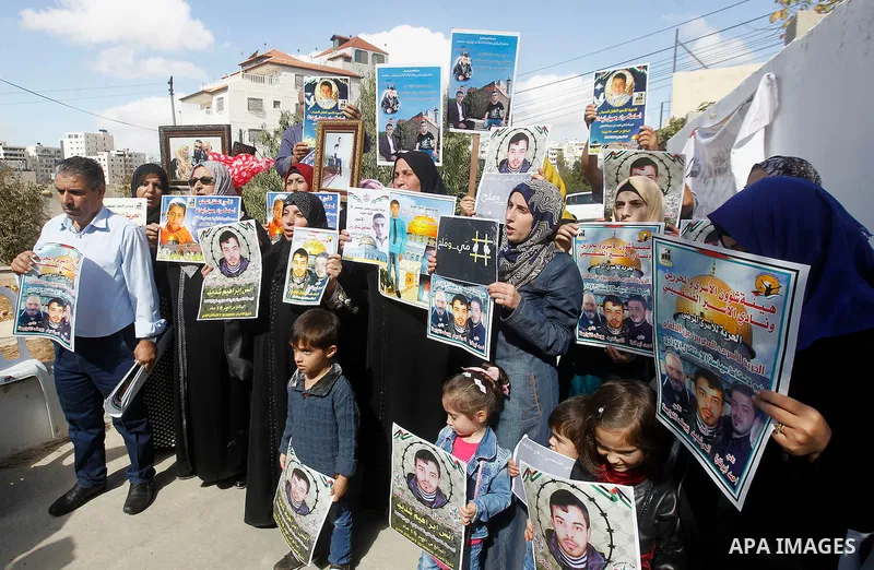 Palestinians hold banners during a protest to show solidarity with Palestinian prisoners in Israeli jails, in front of Red cross office in the West Bank city of Hebron, on October 31, 2016. Photo by Wisam Hashlamoun