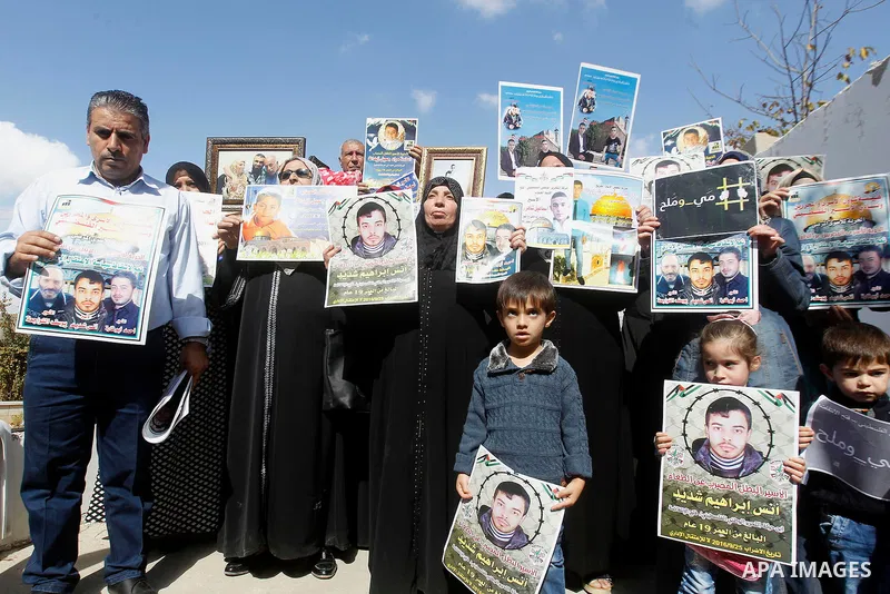 Palestinians hold banners during a protest to show solidarity with Palestinian prisoners in Israeli jails, in front of Red cross office in the West Bank city of Hebron, on October 31, 2016. Photo by Wisam Hashlamoun