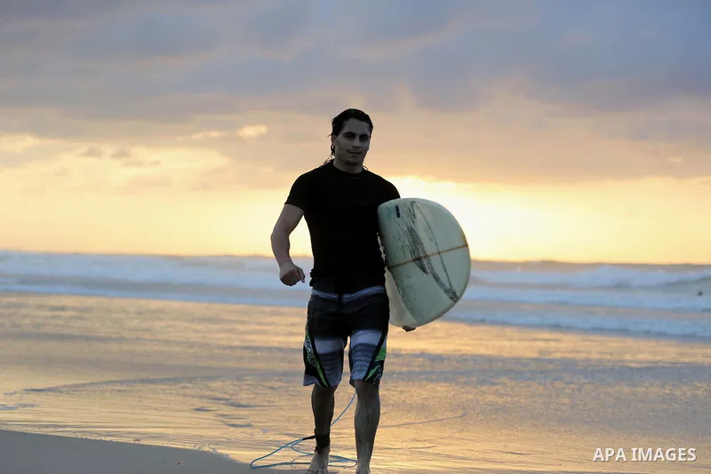A Palestinian surfer walks along the beach of Gaza City on November 2, 2016. Photo by Yasser Qudih